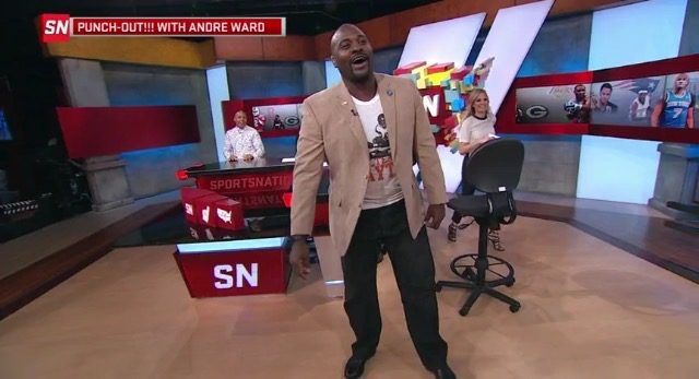 Marcellus Wiley on the ESPN SportsNation set wearing a white 500 Level player-graphic T-shirt under a tan blazer.