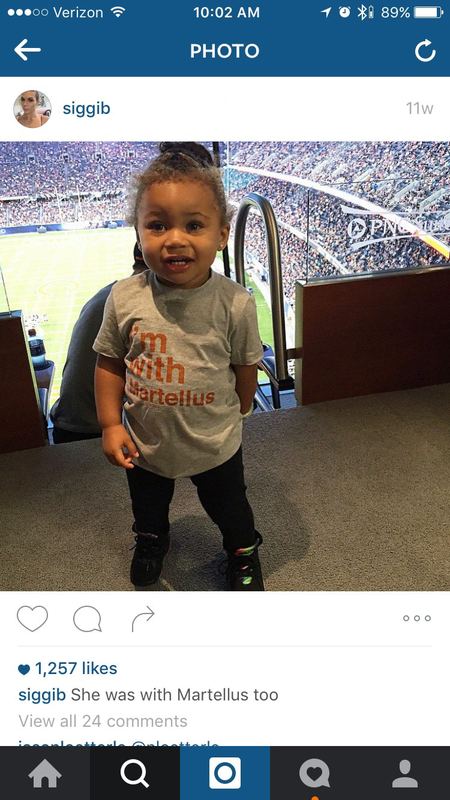 Martellus Bennett's toddler daughter at Soldier Field wearing a gray 500 Level 'I'm with Martellus' kids T-shirt.