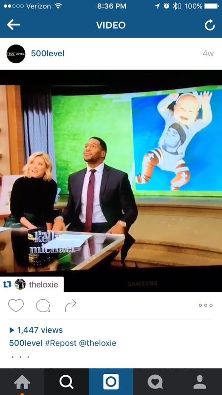 Kelly Ripa and Michael Strahan on Live! with a photo of a baby in a 500 Level Tom Brady onesie on screen.