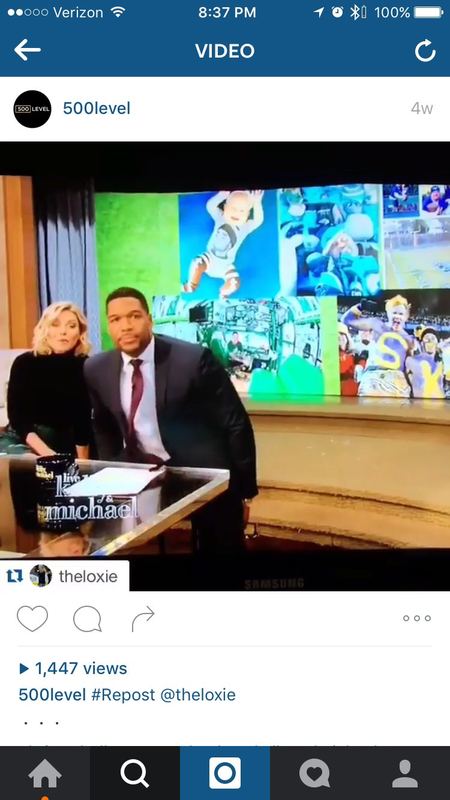 Wide shot of the Live! with Kelly and Michael set showing the 500 Level Tom Brady onesie photo among fan images.