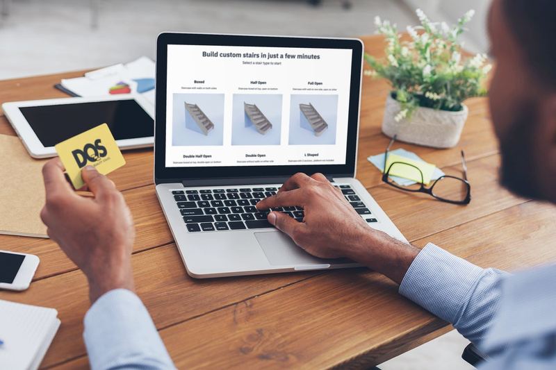 over the shoulder mockup of a man working on his macbook and holding a business card 36933 r el2 — DQS Pictures